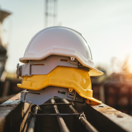 white and yellow helmet on steel in construction site
